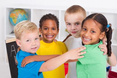 A group of children holding another while smiling