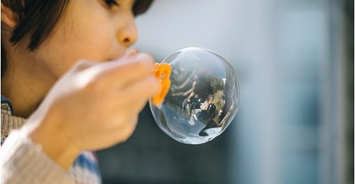 A child using a bubble wand to blow bubbles