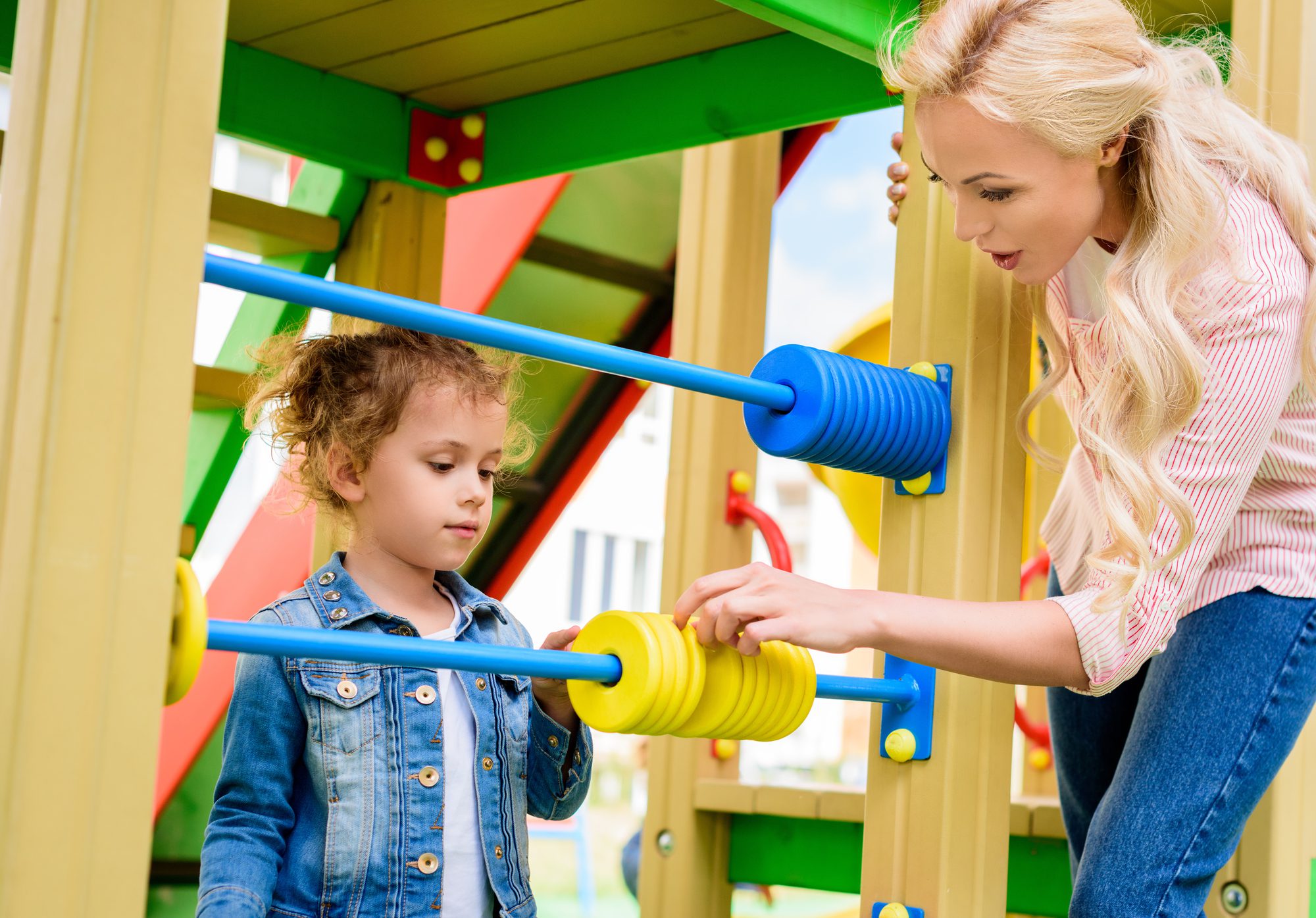 A teacher helping a student count with playground toys