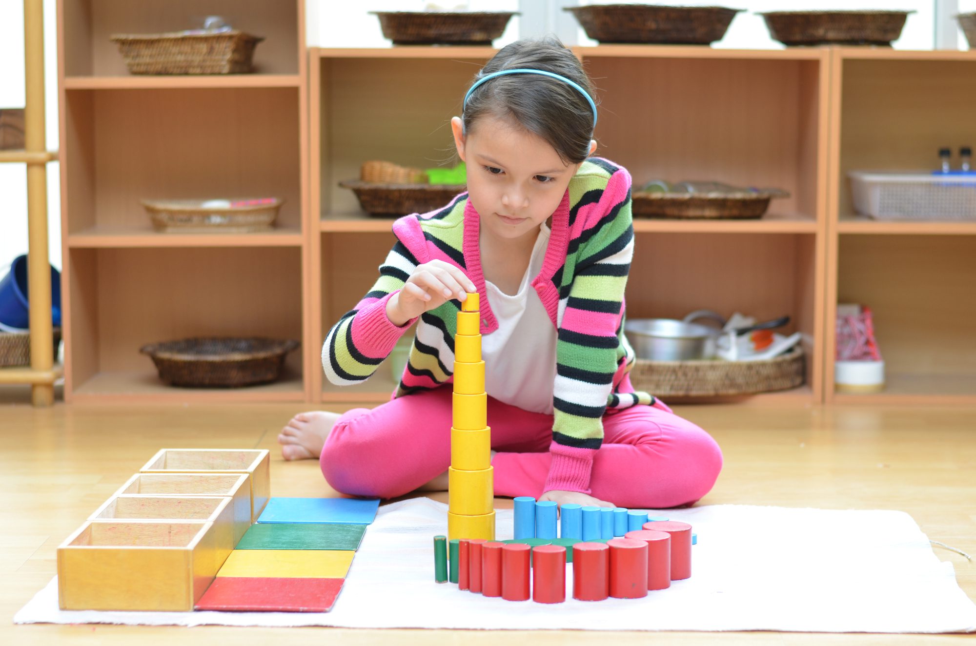 A young girl stacking different colored blocks at Meadow Montessori School in South Richmond, TX