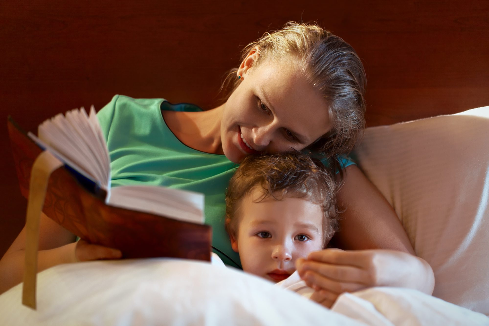 A mother reading a book to her child in bed