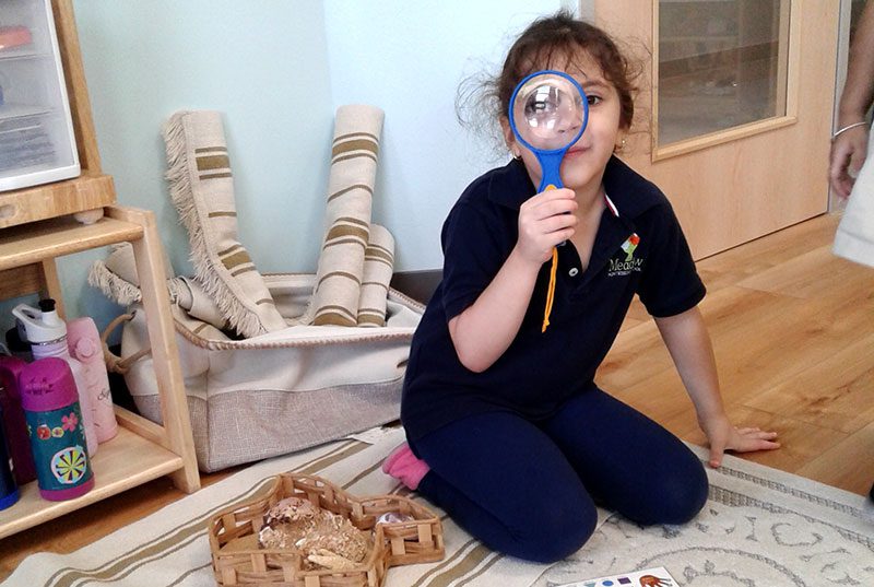 A child from Meadow Montessori School playing with a magnifying glass