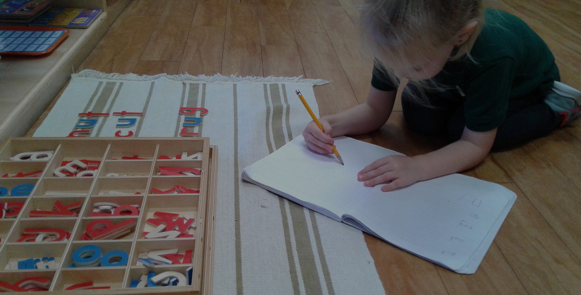 A child tracing letters in a notebook at Meadow Montessori School in South Richmond, TX