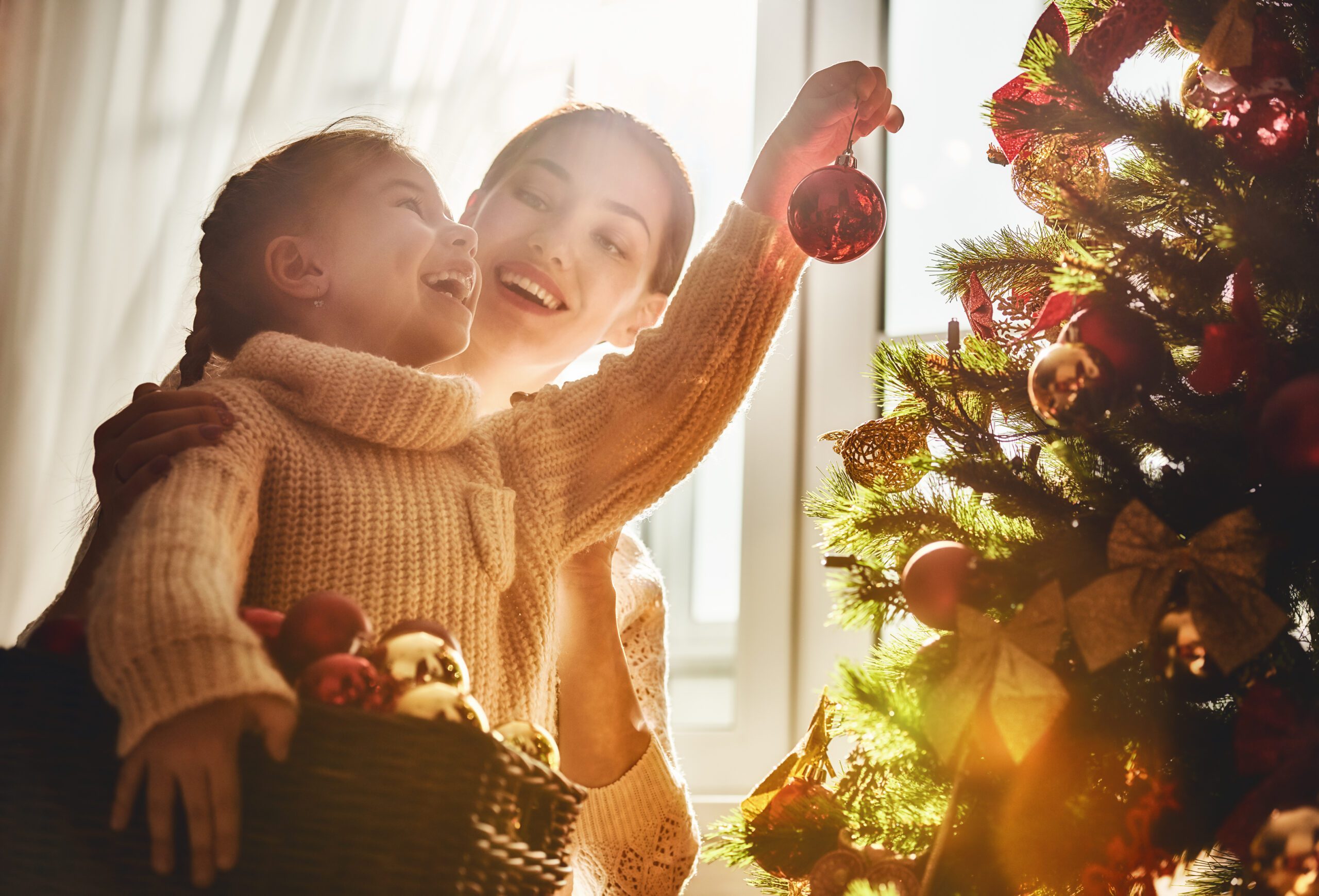 woman and child decorating a christmas tree