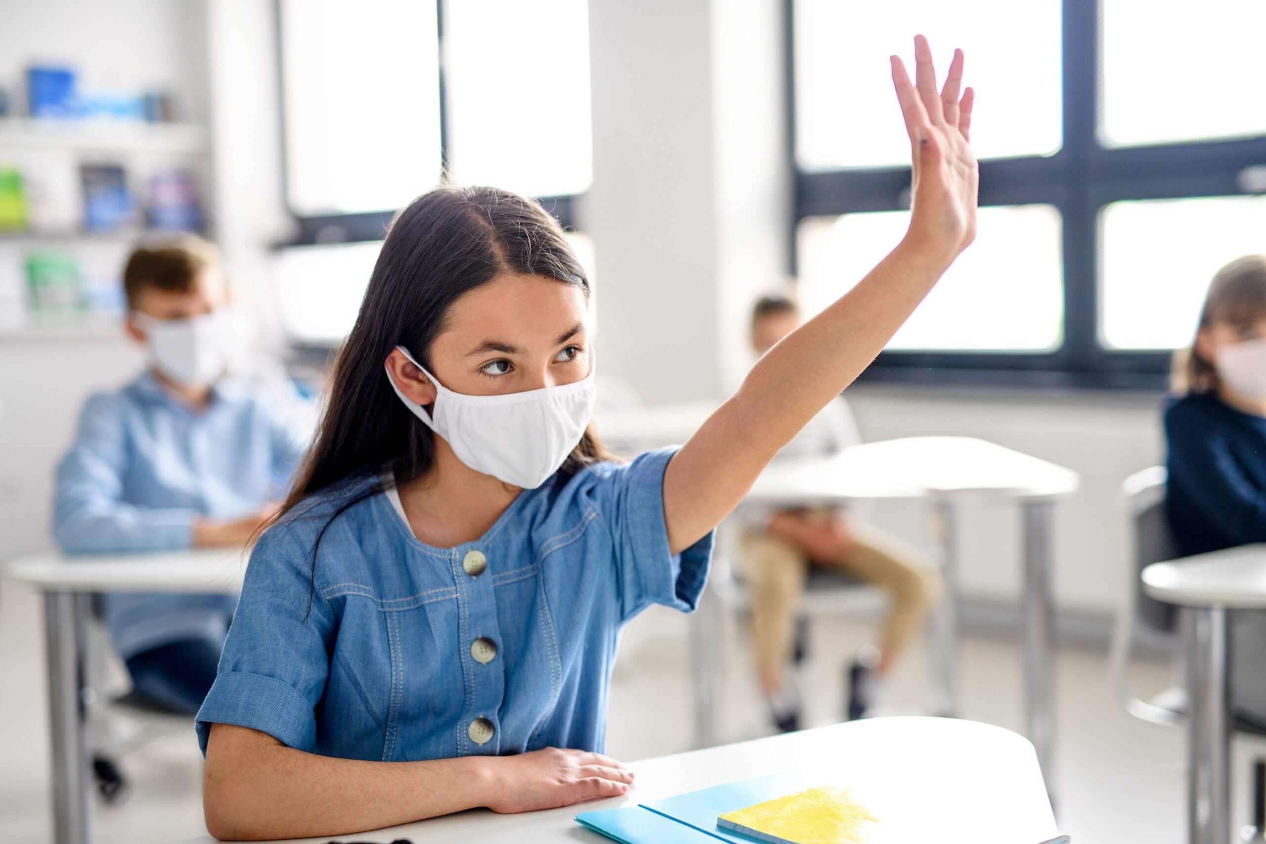 student in a mask raising hand