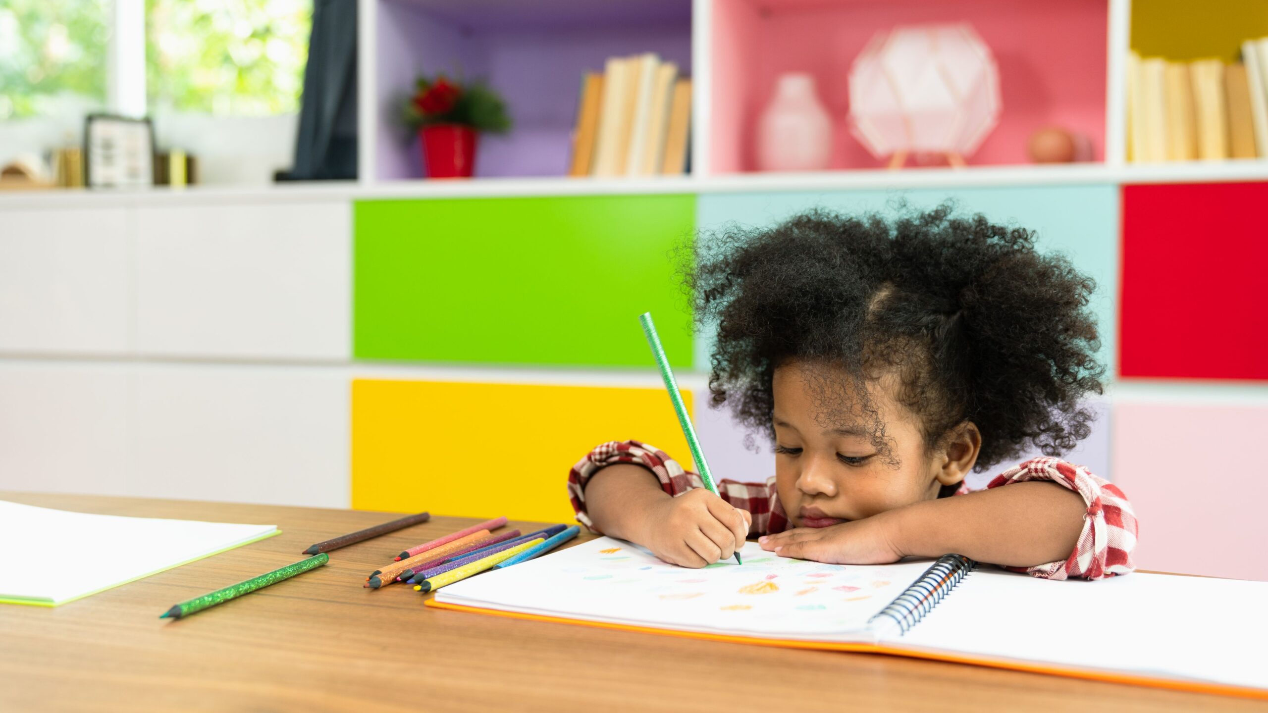 little girl learning from home and drawing in a notebook