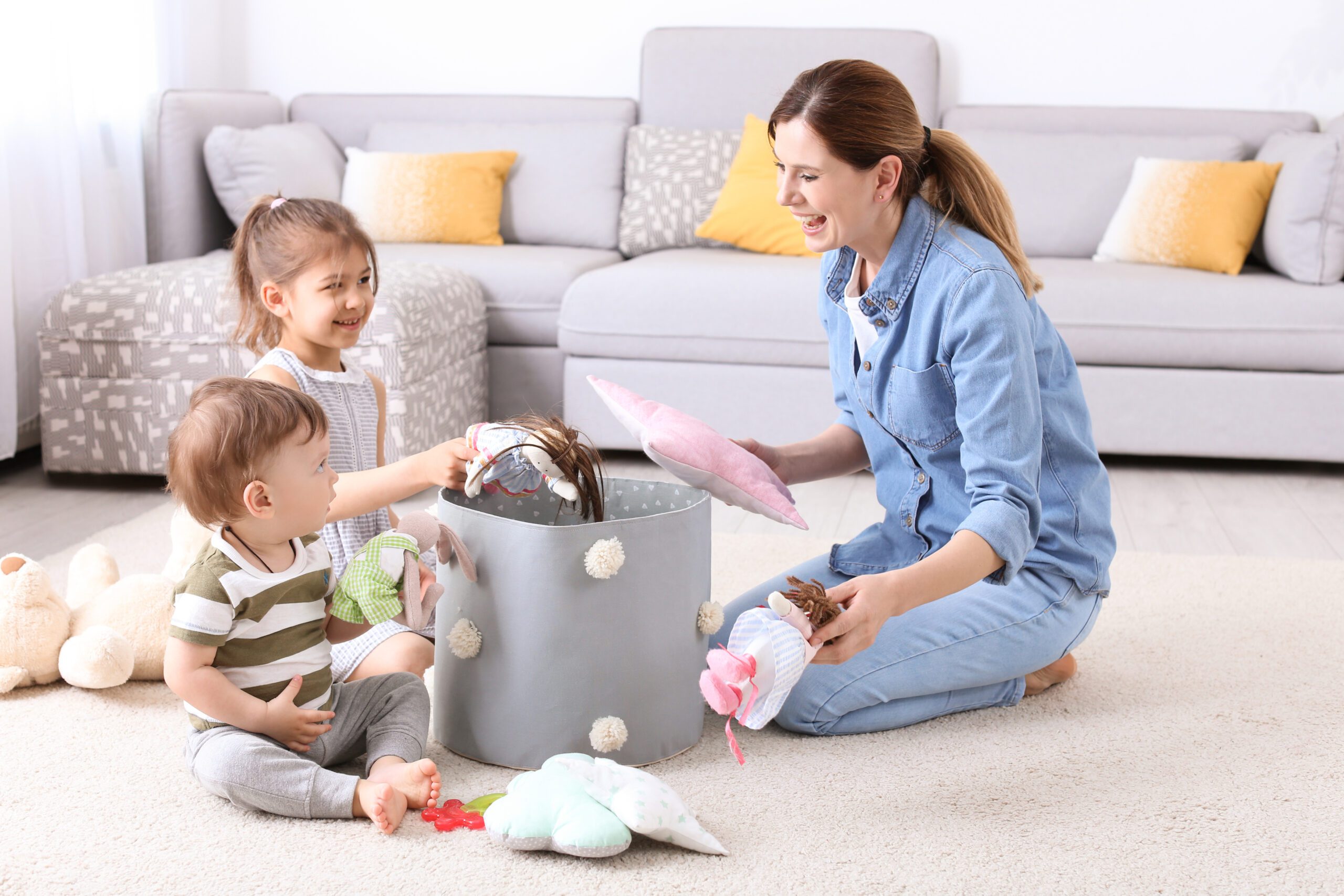 Mother helping young children put their toys away